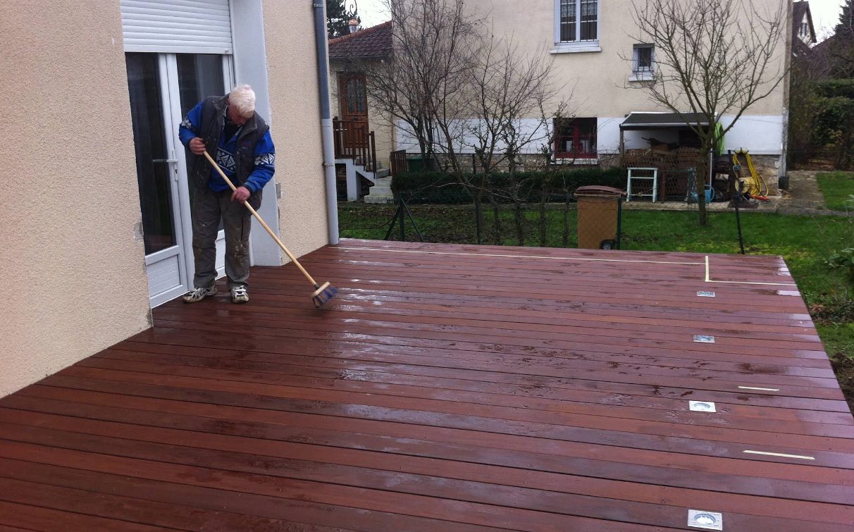 Gérard Mioque à l'ouvrage sur une terrasse en bois exotique